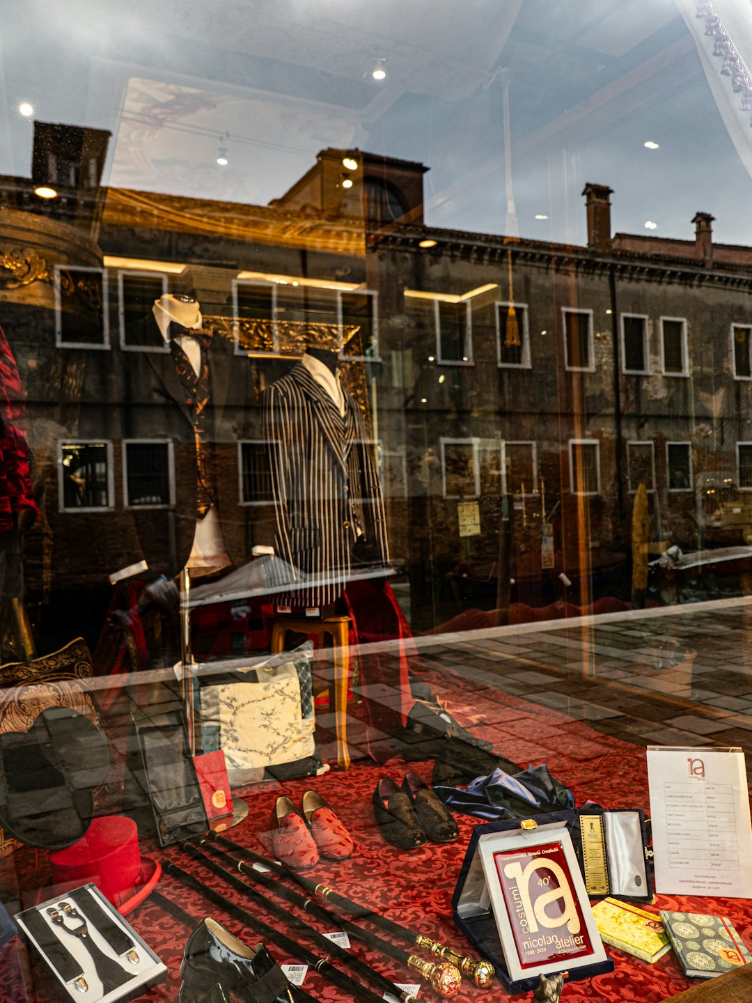 Mannequins in classic suits display tailor shop window.
