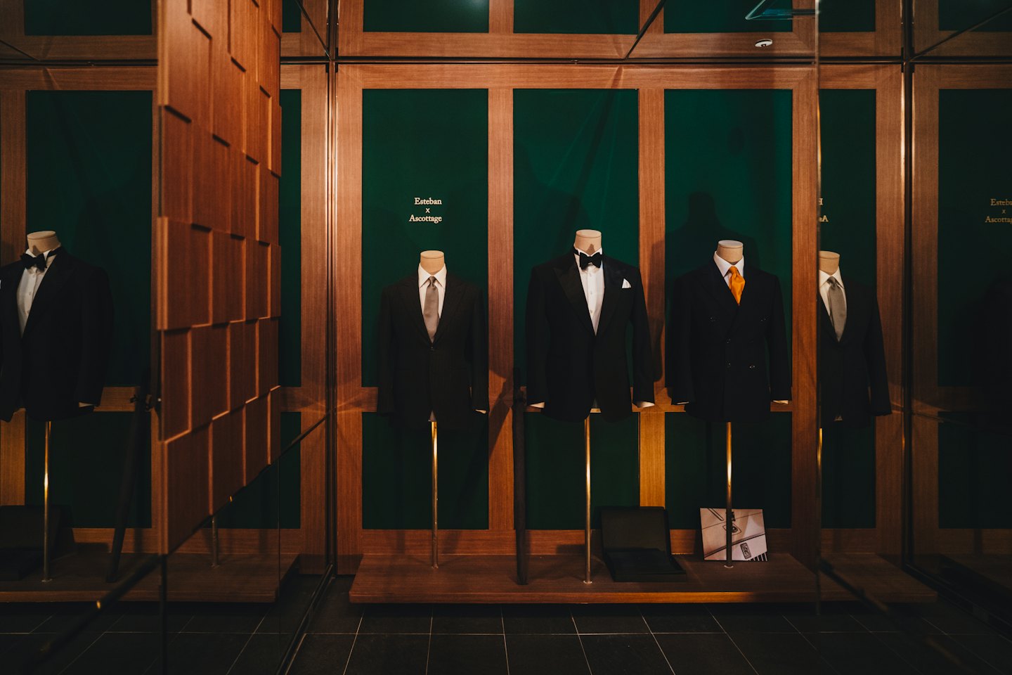 Mannequins wear formal suits inside glass display cases.