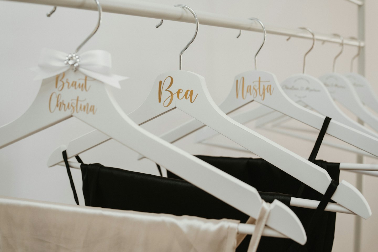 Personalized wooden clothes hangers hanging on a white rail.